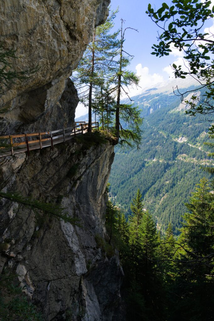 A breathtaking view of a narrow mountain path atop a cliff in the Swiss Alps, showcasing rugged beauty.